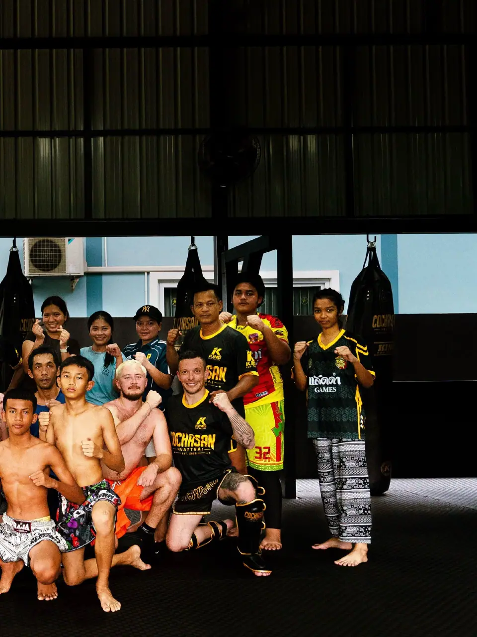 A class with coaches posing in the gym
